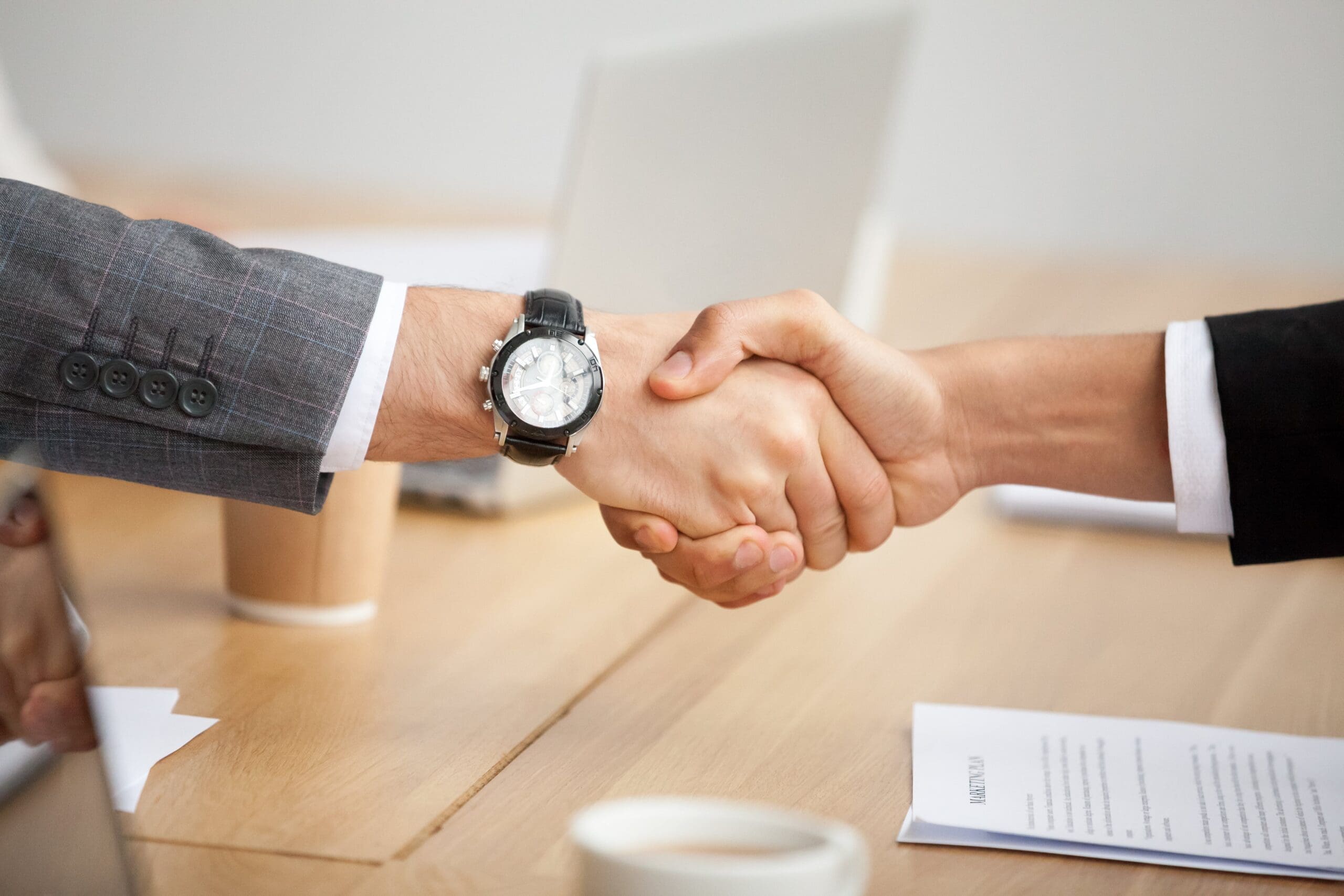 closeup view handshake two businessmen suits shaking hands min scaled