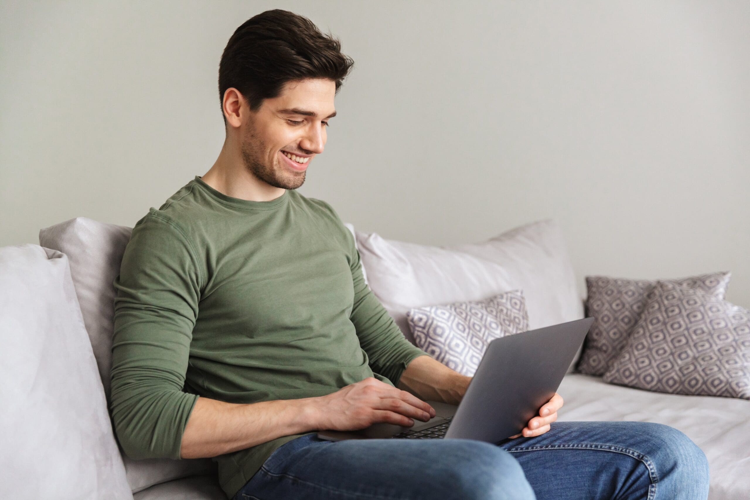 smiling young man using laptop computer min scaled